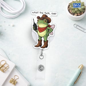 May include: A badge reel featuring a cartoon frog wearing a cowboy hat, boots, and a red bandana, holding a walkie-talkie. The text "what the fuck, over" is above the frog.