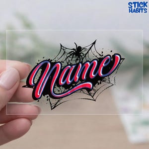 May include: A clear sticker with the word "Name" in a red, white, and blue script font, overlaid on a black spiderweb design with a black spider. The sticker has a "Stick Habits" logo in the top right corner.