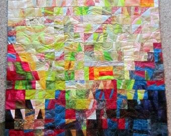 May include: A colorful patchwork quilt with a variety of fabrics and patterns. The quilt is made up of squares and rectangles of different sizes and colors, including red, blue, green, yellow, and white. The quilt is quilted with a simple stitch pattern.