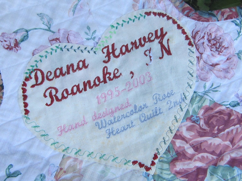 May include: A heart-shaped fabric label with embroidered text: "Deana Harvey Roanoke, 1995-2003, Hand designed, Watercolor Rose, Heart Quilt, Inc."