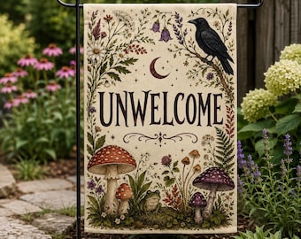 May include: A rectangular garden flag featuring the text UNWELCOME in dark lettering. The design includes a black crow perched on a branch, a crescent moon, various wildflowers, ferns, and several mushrooms with a small frog sitting at the base.