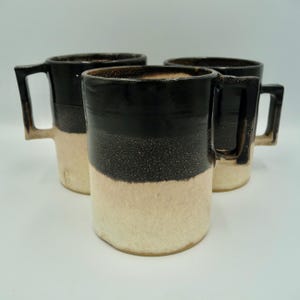 Taza de gres blanco liso con esmalte negro brillante y avena.