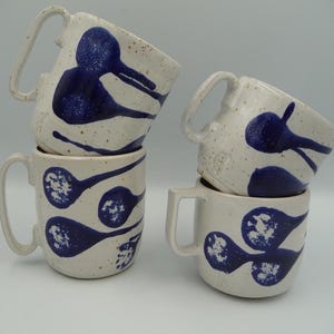 Puede incluir: Un juego de tres tazas de cerámica con un acabado mate moteado. Las tazas son en tonos crema, gris claro y gris oscuro. Cada taza tiene un diseño simple y minimalista y un asa redondeada.
