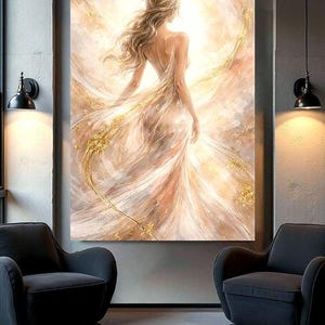 May include: A large canvas art print shows a woman in a flowing gown, seen from behind. The artwork uses soft beige, gold, and white tones, with an emphasis on light and movement. The woman's hair flows down her back, creating a sense of motion.