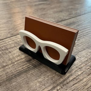 Glasses Business Card Holder on a wood background holding business cards.