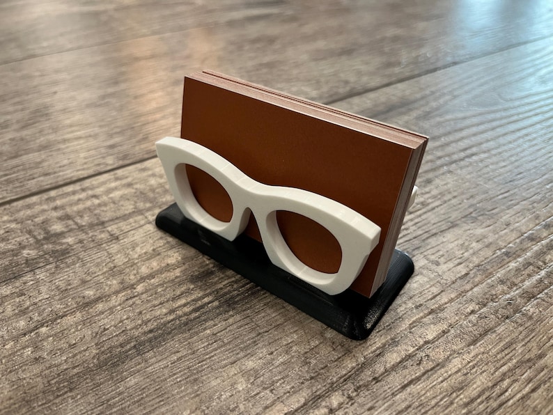 Glasses Business Card Holder on a wood background holding business cards.