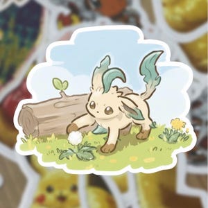 Pode incluir: Um autocolante com uma criatura de desenho animado com pelo castanho claro e detalhes verdes, num cenário relvado com um tronco e um céu azul. O autocolante é rodeado por outros autocolantes, incluindo Pikachu.