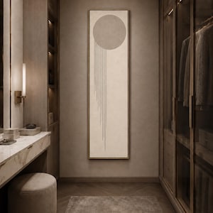 May include: A tall, rectangular framed wall art piece featuring a large, solid beige circle at the top with thin, vertical black lines extending downwards from the right side of the circle, set against a light cream background within a thin frame.