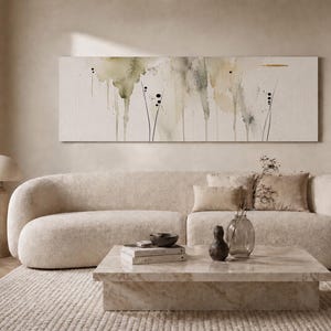 May include: A long rectangular canvas painting featuring abstract watercolor washes in muted green, beige, and gray tones with delicate black ink line details and small dots, displayed horizontally on a plain wall above a curved beige sofa.