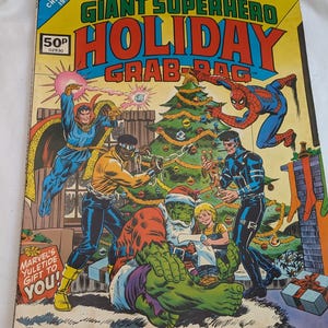 Puede incluir: Un cómic vintage de Marvel Treasury Edition titulado "Giant Superhero Holiday Grab-Bag". La portada presenta a varios superhéroes, incluidos Spider-Man y Hulk, celebrando la Navidad. El cómic es de 1975 e incluye el texto "Marvel's Yuletide Gift to You!"