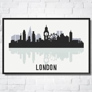 Puede incluir: Una impresión artística enmarcada que presenta una silueta en blanco y negro del horizonte de Londres, incluyendo el Big Ben y el London Eye. La palabra "LONDON" está impresa en letras negras debajo.