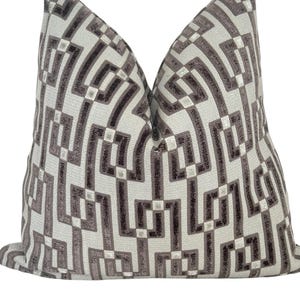 May include: A decorative throw pillow with a geometric pattern in shades of gray and off-white. The pillow features a repeating design of interlocking shapes, creating a modern and stylish look. The pillow is a square shape.