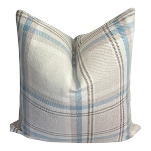 Peut inclure: Un coussin carr&eacute; avec un motif &agrave; carreaux tiss&eacute; dans des tons doux de bleu clair, beige et blanc. Le tissu pr&eacute;sente un tissage textur&eacute; visible, et le motif se compose de lignes horizontales et verticales qui se croisent pour former une grille.