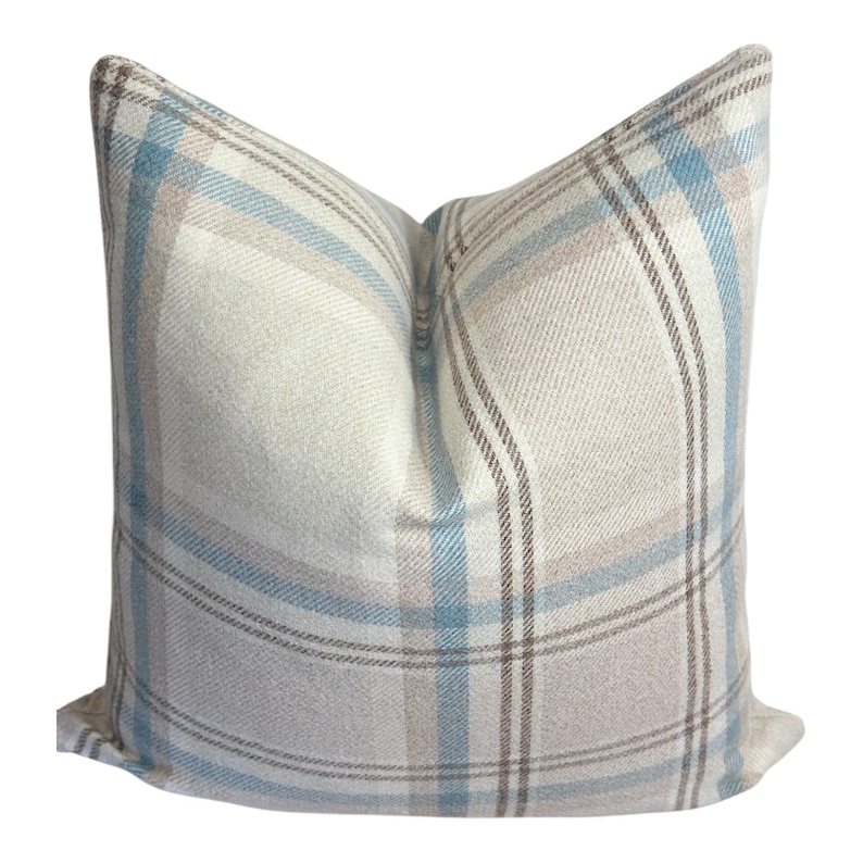 Peut inclure: Un coussin carr&eacute; avec un motif &agrave; carreaux tiss&eacute; dans des tons doux de bleu clair, beige et blanc. Le tissu pr&eacute;sente un tissage textur&eacute; visible, et le motif se compose de lignes horizontales et verticales qui se croisent pour former une grille.