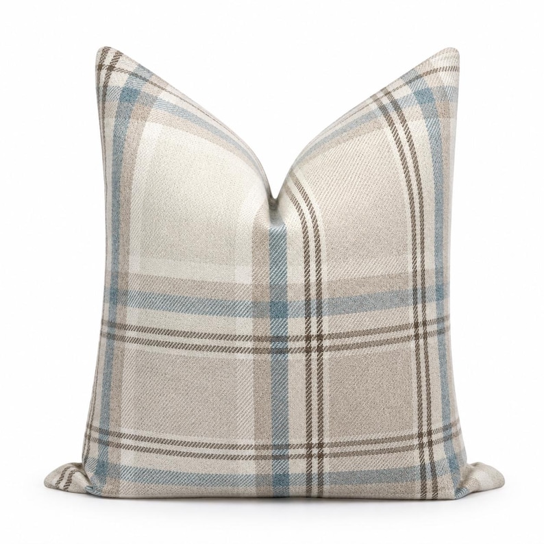 Peut inclure: Un coussin carr&eacute; avec un motif &agrave; carreaux tiss&eacute; dans des tons beige, bleu clair et marron fonc&eacute;. Le tissu pr&eacute;sente un aspect textur&eacute; avec des lignes horizontales et verticales qui se croisent pour former un motif &agrave; grille classique.