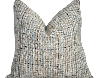 Peut inclure: Un coussin carré en tissu tissé texturé avec un motif à carreaux multicolores. Le design se compose de lignes entrecroisées dans des tons bleu clair, beige et marron foncé, créant un effet de grille classique sur toute la surface du coussin.