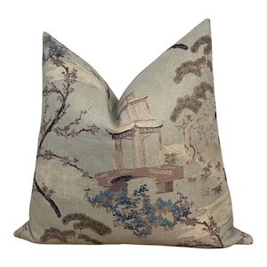 May include: A square throw pillow featuring a light sage green background with a detailed woven pattern. The design depicts a pagoda structure, stylised trees, and floral elements in shades of brown, blue, and cream, creating a textured appearance.