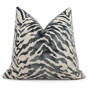 May include: A square throw pillow featuring a dark charcoal gray and cream-colored zebra stripe pattern. The fabric has a soft, plush texture with a subtle sheen, and the pillow is plumped to create a distinct peak at the top center.