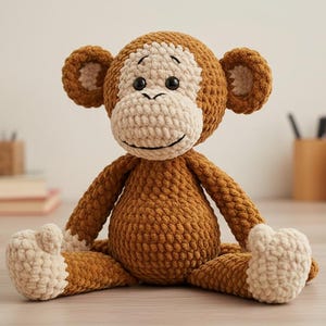 以下が含まれることがあります： 茶色とクリーム色の手作りの編み物モンキー人形。 ぬいぐるみは笑顔の顔、大きな耳をしており、足を伸ばして座っています。 猿は柔らかく、抱きしめたくなるおもちゃです。