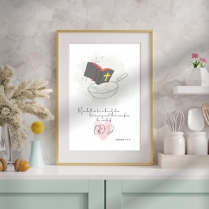 Op de afbeelding: Een ingelijste print met een gouden rand. De illustratie toont een bijbel, een kruis en een mengkom. De tekst luidt: 'De mens zal niet van brood alleen leven, maar van elk woord dat uit de mond van GOD komt.' Mattheüs 4:4-6.