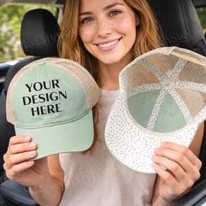 May include: Two light green trucker hats with mesh backs are held up. One hat is right-side-out, displaying the text "YOUR DESIGN HERE" in black. The other hat is inside-out, showing a white interior with small black polka dots. The hats are a light green color.