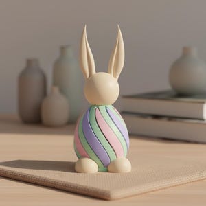 May include: A decorative Easter bunny figurine. The bunny has a cream-colored head and ears, with a body featuring pastel stripes of green, purple, and pink. The bunny is sitting on a beige placemat.