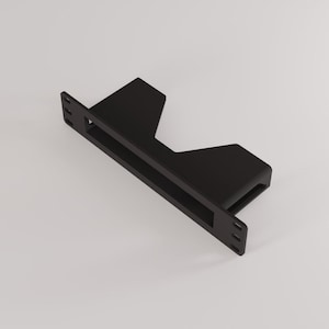 Op de afbeelding: Een zwarte metalen beugel met een rechthoekige opening en montagegaten. De beugel heeft een trapsgewijs ontwerp met twee schuine secties. Het object wordt tegen een witte achtergrond getoond.