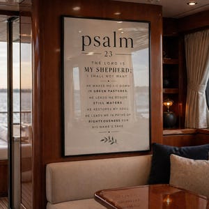 Könnte beinhalten: Ein gerahmter Druck mit dem Text "Psalm 23" in einem Bootsinnenraum. Der Text enthält den Vers "Der Herr ist mein Hirte; mir wird nichts mangeln." Der Druck ist in einem schwarzen Rahmen, und der Innenraum hat Holzverkleidungen und beige Sitzgelegenheiten.