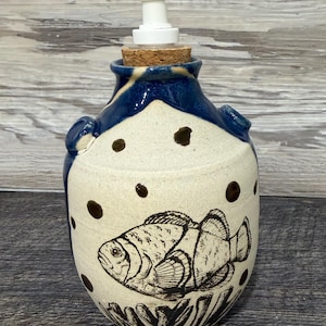 May include: A white ceramic mug with a black handle and the text "But first, coffee" in a handwritten style. The mug is on a white surface. The mug is approximately 4 inches tall.