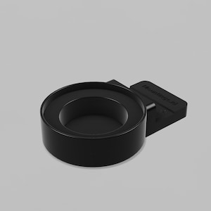Puede incluir: Un soporte circular negro para vasos con una base de fijación rectangular plana. La base presenta el texto en relieve Mountings.nl. El objeto tiene un acabado mate liso y un centro hueco diseñado para sujetar un recipiente cilíndrico.
