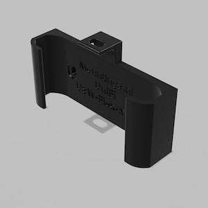 May include: A black plastic mounting bracket featuring a curved U-shaped design with a top tab and a central screw hole. The surface is embossed with the text Mountings.nl, UniFi, and USW-Flex-Mini, indicating its specific functional compatibility.