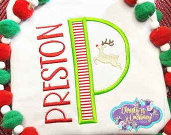 May include: White long-sleeve shirt with red embroidered text "PRESTON" and a green and red striped letter "P" with a reindeer inside. The letter "P" is outlined in green.