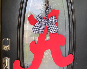 May include: A red wooden letter A with a black and white checkered bow hanging on a black door.