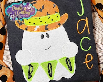 May include: Black t-shirt with a white ghost wearing an orange and green hat with the word "BOO" on a banner. The name "Jace" is embroidered in green on the right side of the shirt.