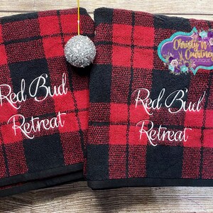 May include: Two red and black buffalo plaid towels with the text "Red Bud Retreat" embroidered in white.