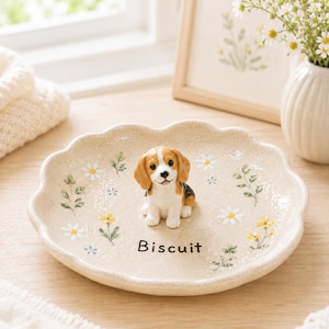 Puede incluir: Un plato decorativo de cerámica en color beige moteado con borde festoneado. Presenta una figura tridimensional de un beagle en el centro, detalles florales pintados y la palabra Biscuit impresa en letras negras sobre la base.