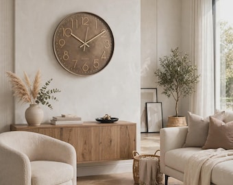 May include: A round wall clock with a dark bronze finish, featuring raised gold-toned numerals and matching slender hands. The clock face has a textured surface with a subtle metallic sheen and the word Quartz printed in small gold lettering.