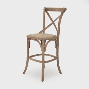 Puede incluir: Taburete de bar de madera con acabado natural. El taburete presenta un respaldo en forma de X y un reposapi&eacute;s redondo. El asiento est&aacute; tapizado en tela de color neutro. El dise&ntilde;o es r&uacute;stico y adecuado para una cocina o bar.