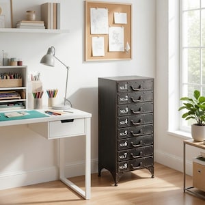 May include: A black metal cabinet with eight drawers, each labeled with a number in white. The cabinet has a vintage industrial design, with metal handles and legs. The cabinet is in a home office setting, next to a white desk and a window.