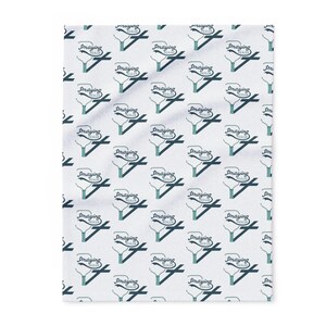 May include: White blanket featuring a repeating pattern of pickleball paddles and the words "Praying Pickles" in a script font. The paddles and text are in teal and dark blue.