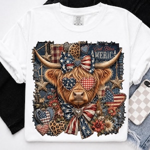 May include: White t-shirt featuring a Highland cow design. The cow wears heart-shaped sunglasses and bows in patriotic red, white, and blue. The design includes the text "God Bless America" and floral and star accents.