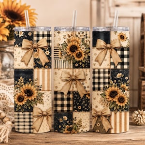 May include: Three cylindrical tumblers with clear lids and straws, featuring a patchwork design of sunflowers, black and white buffalo plaid, and beige stripes, accented with tan bows throughout the patterns on a cream-colored background.