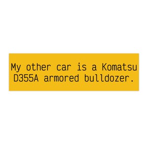 May include: A yellow rectangle with black text that reads: "My other car is a Komatsu D355A armored bulldozer."