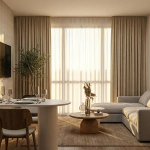 Può includere: Un moderno soggiorno con una palette di colori neutri. Include un divano angolare grigio, un tavolino rotondo, un tavolo da pranzo con sedie in legno e grandi tende beige. Opere d'arte e una TV sono montate sulle pareti.