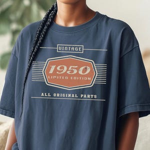 May include: Navy blue t-shirt with a vintage "1950 Limited Edition" design in orange and white. The shirt also features the text "All Original Parts" and the Comfort Custom Tees logo.