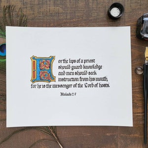 May include: A white sheet of paper with black calligraphy that reads "or the lips of a priest should guard knowledge and men should seek instruction from his mouth, for he is the messenger of the Lord of hosts. Malachi 2:7". The calligraphy is in a decorative font with a large initial letter "E" in blue, red, and gold.