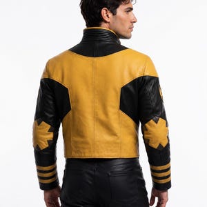 Op de afbeelding: Een leren jas met een mosterdgeel en zwart kleurblokontwerp. De jas heeft een hoge kraag met geribbelde details, stervormige patches op de ellebogen en drie horizontale strepen op elke mouwboord. Gedragen met een zwarte broek.