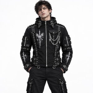 May include: A black hooded jacket featuring a silver front zip, multiple buckled straps, and metal eyelets. The chest displays a white graphic of a winged skull, while a silver chain with cross charms hangs from a pocket flap on the upper chest.
