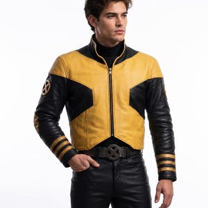 Op de afbeelding: Een zwart en geel leren jack met een hoge kraag, een ritssluiting over de gehele lengte en drie horizontale strepen op elke mouwboord. Het jack is voorzien van ronde X-Men-logo's op de bovenarmen en wordt gedragen met een zwarte broek.