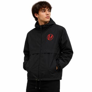 May include: A black windbreaker jacket featuring a hood with adjustable drawstrings, a full-length front zip, and elasticated cuffs. The chest displays a circular red logo with a stylised vertical line and a horizontal dash inside the circle.